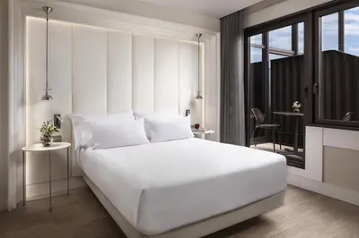 a bedroom with a large white bed and a balcony at NH Collection Barcelona Gran Hotel Calderon in Barcelona