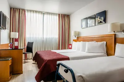 a hotel room with two beds and a desk at Exe Barbera Parc in Barbera del Valles
