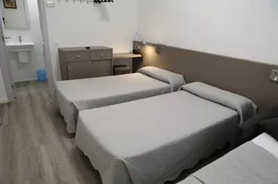 a room with three beds and a sink at Hotel Alguer Camp Nou in Barcelona