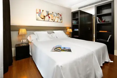 a bedroom with a white bed with a book on it at Hotel Condado in Barcelona