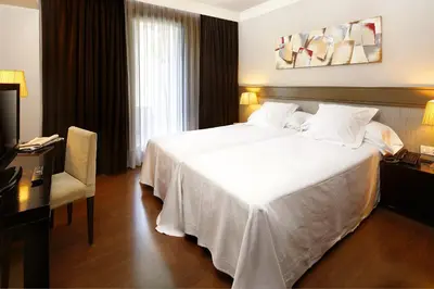 a hotel room with a white bed and a desk at Hotel Condado in Barcelona