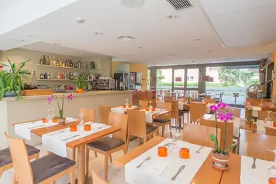 a restaurant with tables and chairs and a counter at Atenea Park Suites & Apartments in Vilanova i la Geltrú
