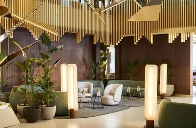a lobby with chairs and plants and lights at Grand Hyatt Barcelona in Barcelona