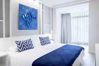 a bedroom with a bed with blue and white pillows at Ibersol Antemare - Adults Only in Sitges