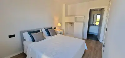 a white bedroom with a white bed with blue pillows at Tina de Vila, en la capital del vino in Vilafranca del Penedès