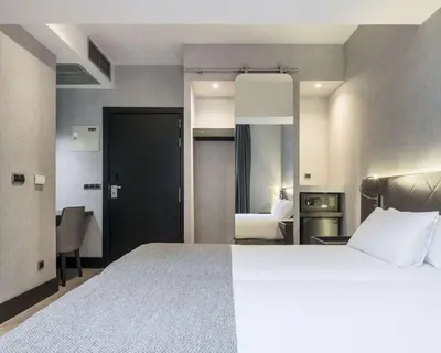 a hotel room with a large bed and a bedroom at Ilunion Bel-Art in Barcelona