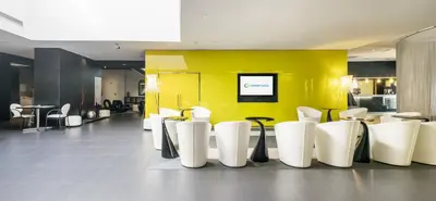 a restaurant with white chairs and a yellow wall at Ilunion Bel-Art in Barcelona
