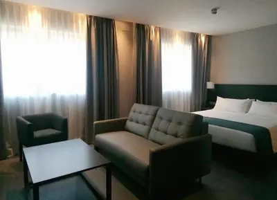 a hotel room with a bed and a couch at HG City Suites Barcelona in Barcelona