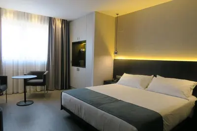 a hotel room with a bed and a table and a window at HG City Suites Barcelona in Barcelona