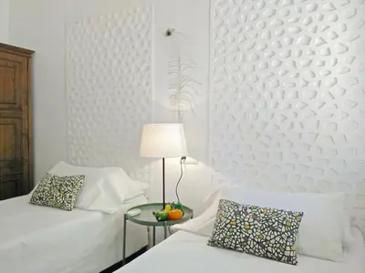 a white room with two beds and a table with a lamp at BizFlats Garden House in Barcelona