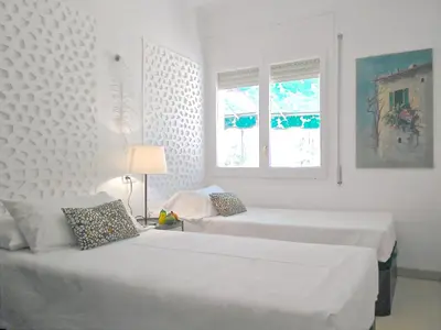 two beds in a white room with two windows at BizFlats Garden House in Barcelona