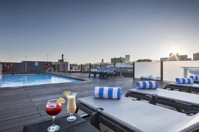 a rooftop patio with two glasses of wine and a pool at Attica 21 Barcelona Mar in Barcelona