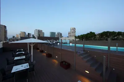 a rooftop deck with a pool and tables and an umbrella at Attica 21 Barcelona Mar in Barcelona