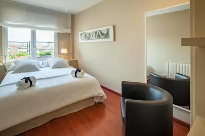 a bedroom with a large bed and a chair at Habitat Apartments Tessa in Barcelona