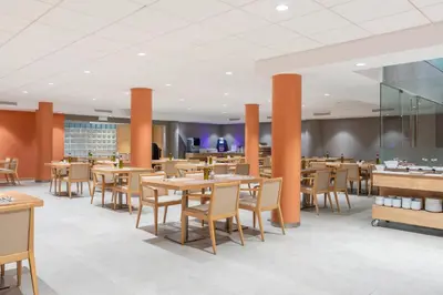 a restaurant with wooden tables and chairs and orange pillars at Acta Sant Just in Sant Just Desvern