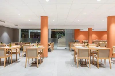 a restaurant with wooden tables and chairs and orange walls at Acta Sant Just in Sant Just Desvern