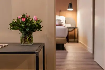 a vase of pink roses sitting on a table in a room at Atenea Rekord Suites Barcelona in Barcelona