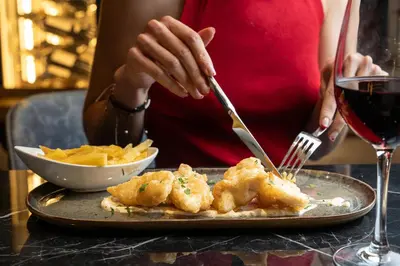 a person holding a fork and knife and a plate of food at Catalonia Plaza Catalunya in Barcelona