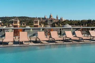 a swimming pool with lounge chairs next to a building at Catalonia Barcelona Plaza in Barcelona