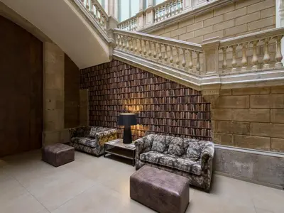 a lobby with two chairs and a table and stairs at Catalonia Portal de l'Angel in Barcelona