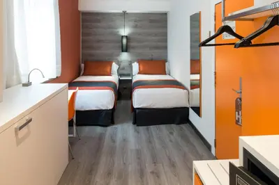 two beds in a room with orange walls at Catalonia Mikado in Barcelona