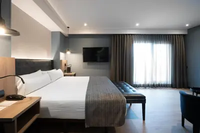 a hotel room with a bed and a desk and a television at Catalonia Atenas in Barcelona