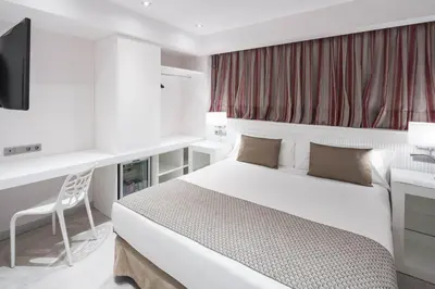 a bedroom with a bed and a desk and a television at Catalonia Roma in Barcelona