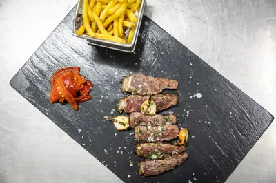 a plate of meat and french fries on a table at Catalonia Gran Hotel Verdi in Sabadell