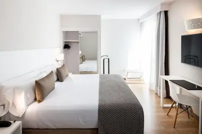 a bedroom with a large white bed and a desk at Catalonia Bristol in Sant Andreu de la Barca