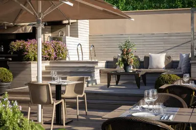 an outdoor patio with tables and chairs and an umbrella at Duquesa de Cardona Hotel 4 Sup by Grup Duquessa in Barcelona