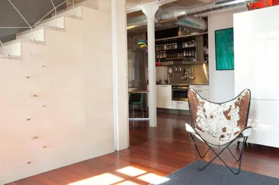 a living room with a chair and a kitchen at Beach Loft Duplex in Barcelona