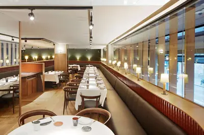 a restaurant with white tables and chairs and windows at Alexandra Barcelona Hotel, Curio Collection by Hilton in Barcelona