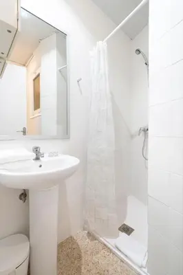 a white bathroom with a sink and a shower at Homenfun Barcelona Park Güell in Barcelona