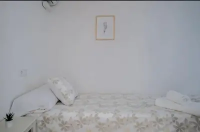 a bed with white sheets and pillows in a room at Apartment close to the beach in Sant Adria de Besos