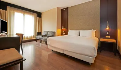 a hotel room with a bed and a desk at NH Barcelona Eixample in Barcelona
