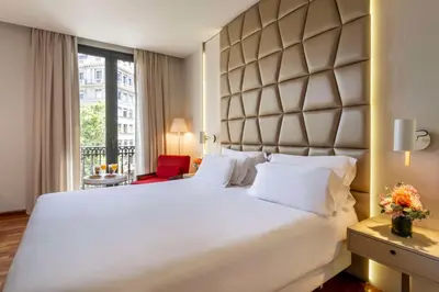 a bedroom with a large white bed with a large headboard at NH Collection Barcelona Podium in Barcelona