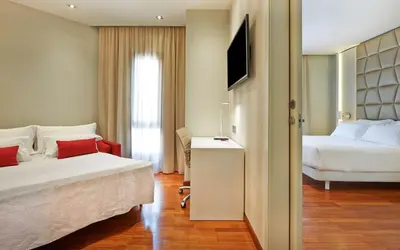 a hotel room with two beds and a television at NH Collection Barcelona Podium in Barcelona