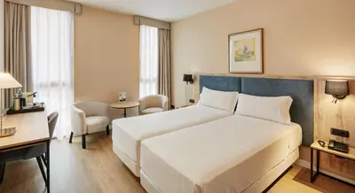 a hotel room with a large white bed and a desk at Sercotel Cornellà Barcelona in Cornellà de Llobregat