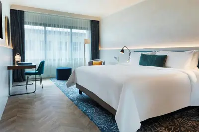 a hotel room with a large white bed and a desk at Renaissance Barcelona Hotel in Barcelona