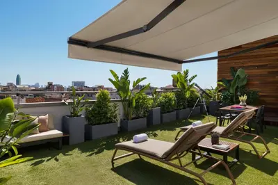 a rooftop patio with chairs and tables and plants at Renaissance Barcelona Hotel in Barcelona