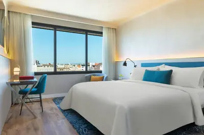 a bedroom with a large bed and a desk and a window at Renaissance Barcelona Hotel in Barcelona