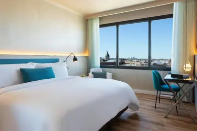 a bedroom with a bed and a desk and a large window at Renaissance Barcelona Hotel in Barcelona