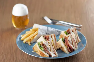 a blue plate with sandwiches and french fries and a glass of beer at AC Hotel Irla by Marriott in Barcelona