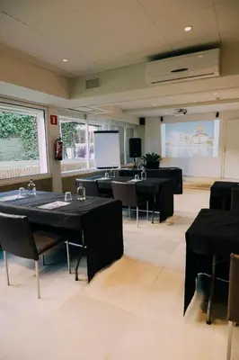 a conference room with tables and chairs and a projection screen at Hotel Subur Maritim in Sitges