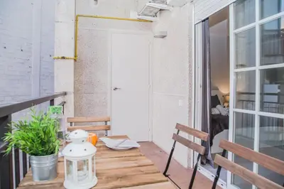 a small balcony with a wooden table and benches at BarcelonaForRent Urban Town Suites in Barcelona