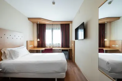 a hotel room with two beds and a mirror at Catalonia La Maquinista in Barcelona