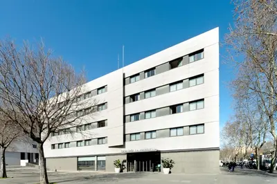 a white building with a tree in front of it at Catalonia La Maquinista in Barcelona
