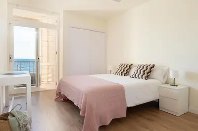 a white bedroom with a bed and a large window at LETS HOLIDAYS Beach front apartment in Gavà Mar, Pine Beach in Gavà