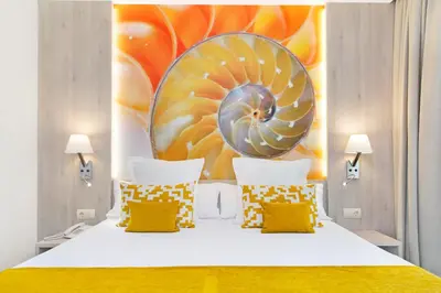 a bedroom with a large bed with yellow and white pillows at Sumus Hotel Stella and Spa 4S Adults Recommended in Pineda de Mar