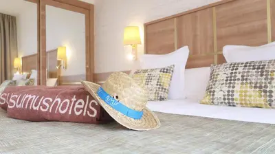 a bed with a hat and pillows on it at Sumus Hotel Stella and Spa 4S Adults Recommended in Pineda de Mar